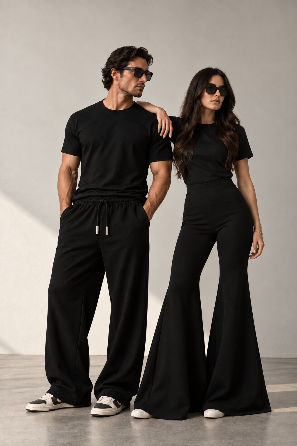 A man and a woman wearing the KŪRK black uniform in a warm, minimal architectural setting